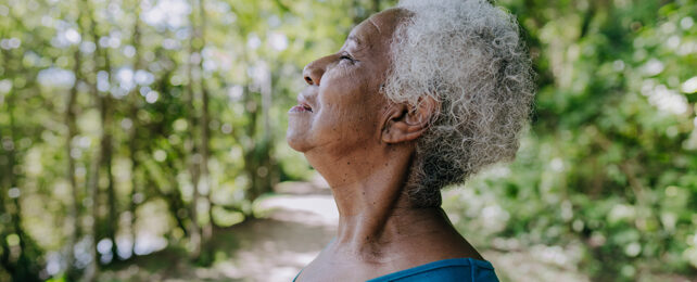 old black woman standing in a forest with her eyes closed